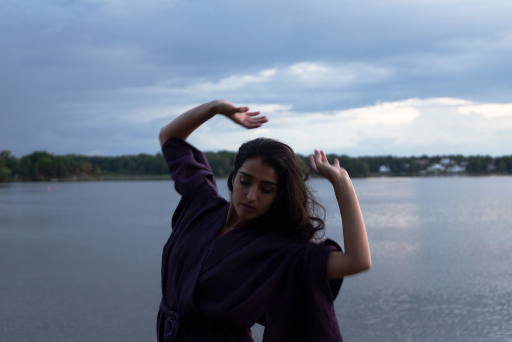 Eine Frau tanzt vor einem See. Sie trägt einen nachhaltigen luftigen Kimono.